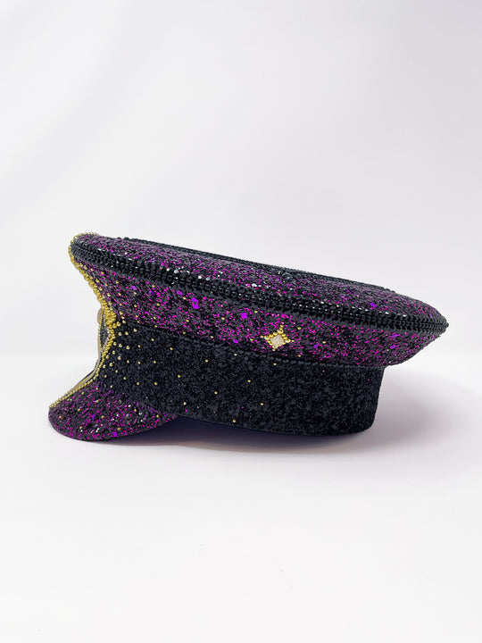 Hand embellished captain hat crafted from an authentic military hat, decorated with black and purple glitter, gold pearl like gems, rhinestones, crystals and geometric jewel detailing. Luxury stage, festival and statement fashion headwear. Handmade, rave, fully lined, high end fashion, costume hat