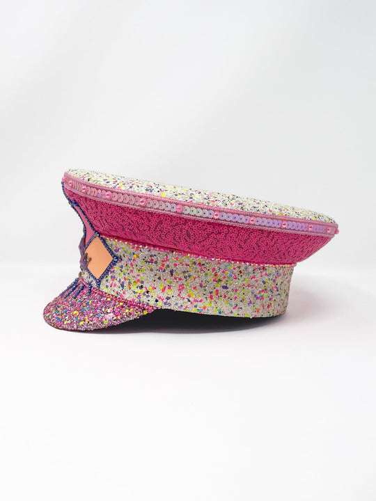 Festival captain hat with pink sequins, colourful glitter peak, Jukebox logo jewel detail, and glow-in-the-dark reflective starburst design – perfect for rave, costume, or party wear. Festival 
fashion,, stage wear
