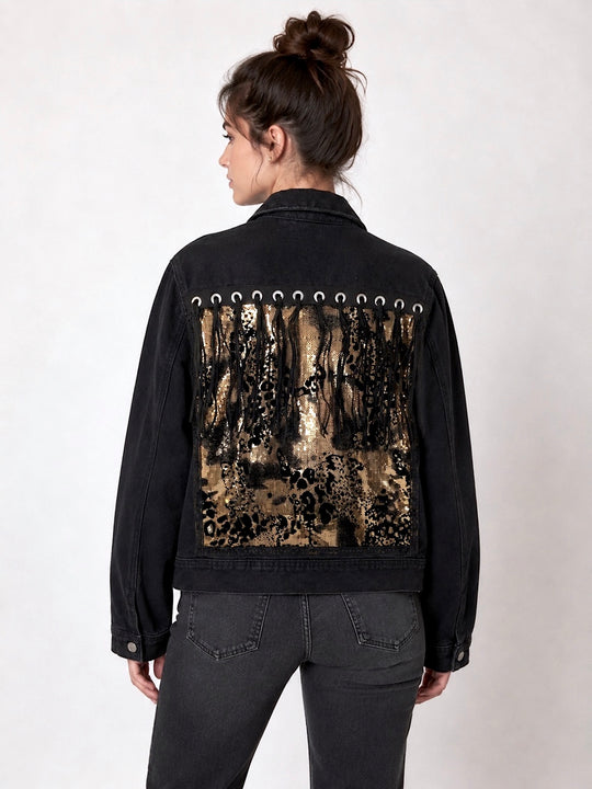 Black denim jacket featuring a black and gold leopard-print sequin appliqué with black tassel detailing across the back, styled on a model. Unique statement festival jacket by Jukebox Fashion. Rave jacket, party jacket, animal print