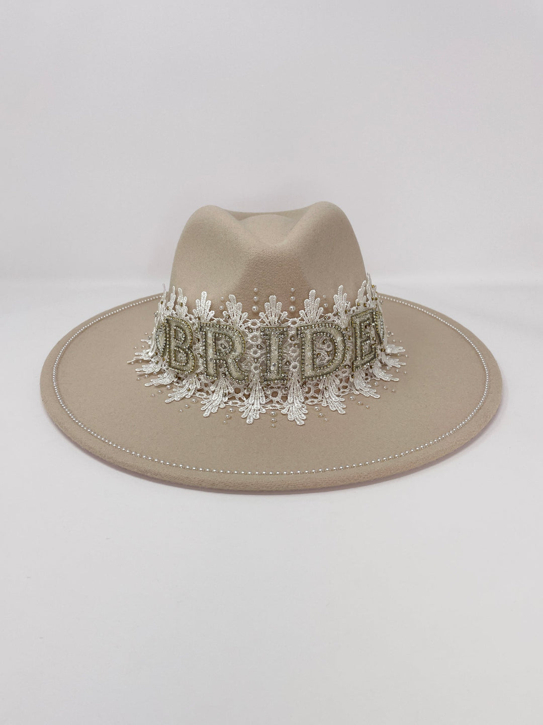 Beige fedora hat featuring interchangeable handmade lace bands with Velcro attachments. Includes three designs: “BRIDE” and “WIFEY” lettering embellished with crystals and pearls, and an elegant floral motif with lace, handmade  flowers and beaded details. A stylish 3-in-1 bridal accessory made in the UK. One size, wide brim fedora, luxury fedora, bride hat, wifey hat, floral hat, hen do