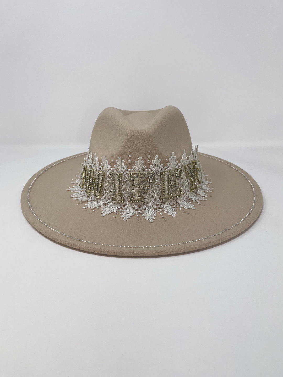 Beige fedora hat featuring interchangeable handmade lace bands with Velcro attachments. Includes three designs: “BRIDE” and “WIFEY” lettering embellished with crystals and pearls, and an elegant floral motif with lace, handmade  flowers and beaded details. A stylish 3-in-1 bridal accessory made in the UK. One size, wide brim fedora, luxury fedora, bride hat, wifey hat, floral hat, hen do