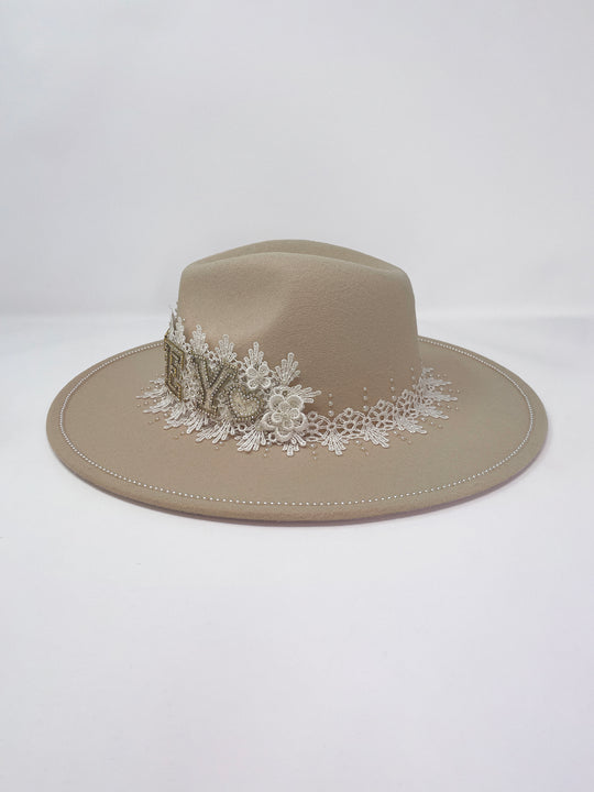 Beige fedora hat featuring interchangeable handmade lace bands with Velcro attachments. Includes three designs: “BRIDE” and “WIFEY” lettering embellished with crystals and pearls, and an elegant floral motif with lace, handmade  flowers and beaded details. A stylish 3-in-1 bridal accessory made in the UK. One size, wide brim fedora, luxury fedora, bride hat, wifey hat, floral hat, hen do