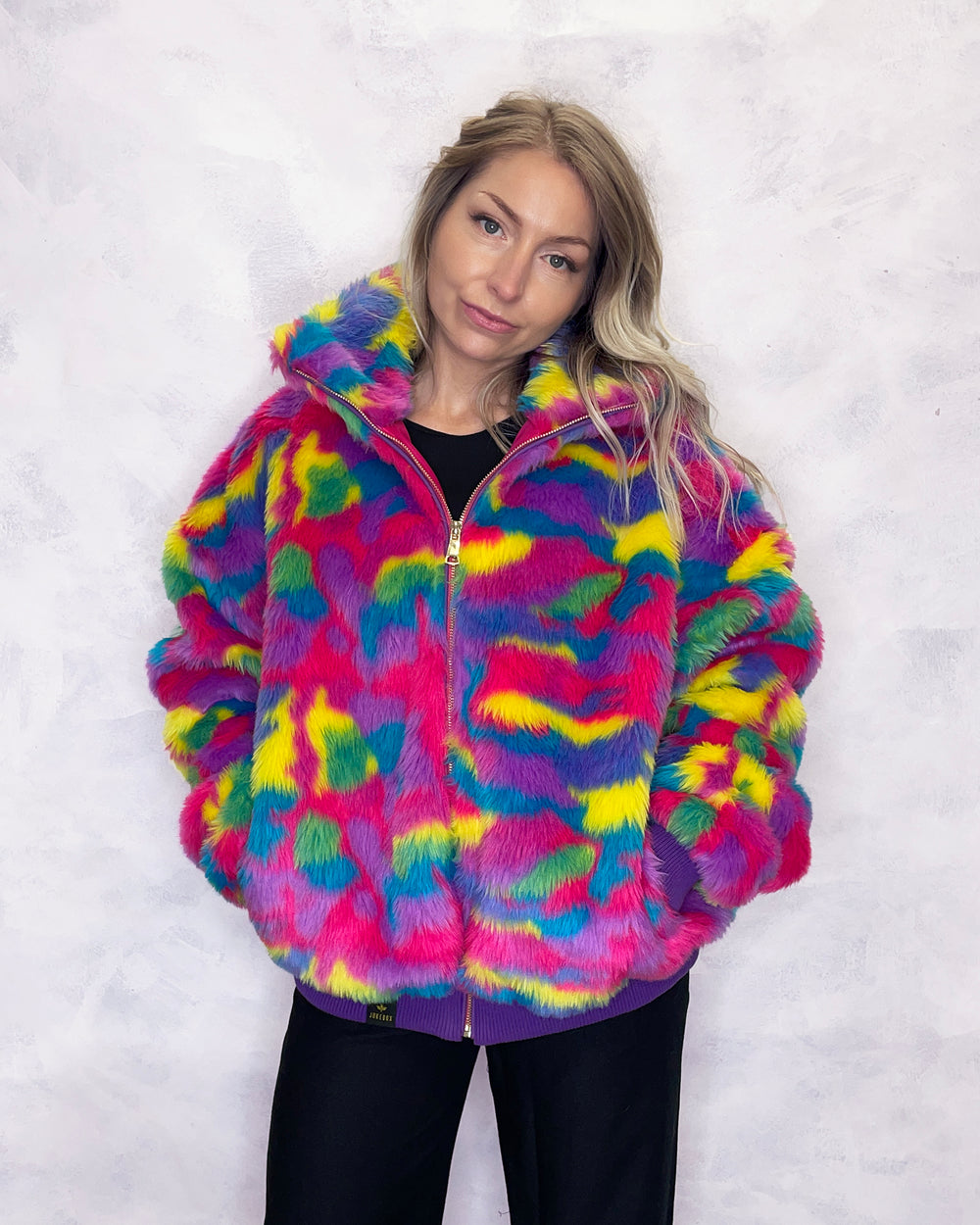 Vibrant multi-coloured faux fur bomber jacket made in the UK, featuring a mix of pink, blue, yellow, green and purple tones. The jacket is fully lined with side pockets, a high collar, and a front zip fastening. ribbed cuffs and waistband. Winter coat, party jacket, festival fur, bright bomber jacket