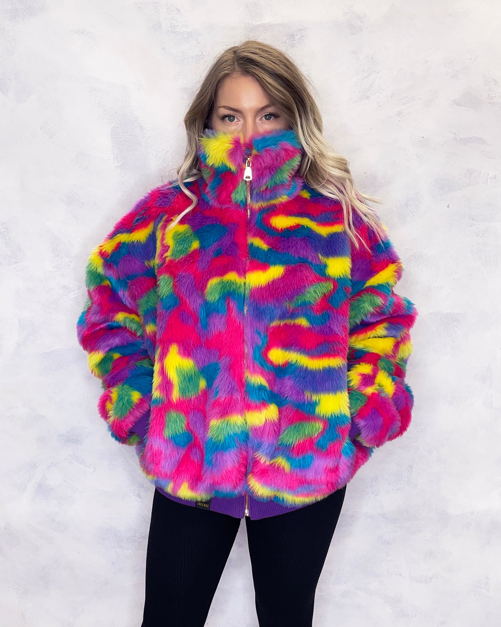 Vibrant multi-coloured faux fur bomber jacket made in the UK, featuring a mix of pink, blue, yellow, green and purple tones. The jacket is fully lined with side pockets, a high collar, and a front zip fastening. ribbed cuffs and waistband. Winter coat, party jacket, festival fur, bright bomber jacket