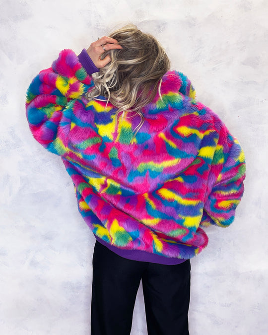 Vibrant multi-coloured faux fur bomber jacket made in the UK, featuring a mix of pink, blue, yellow, green and purple tones. The jacket is fully lined with side pockets, a high collar, and a front zip fastening. ribbed cuffs and waistband. Winter coat, party jacket, festival fur, bright bomber jacket