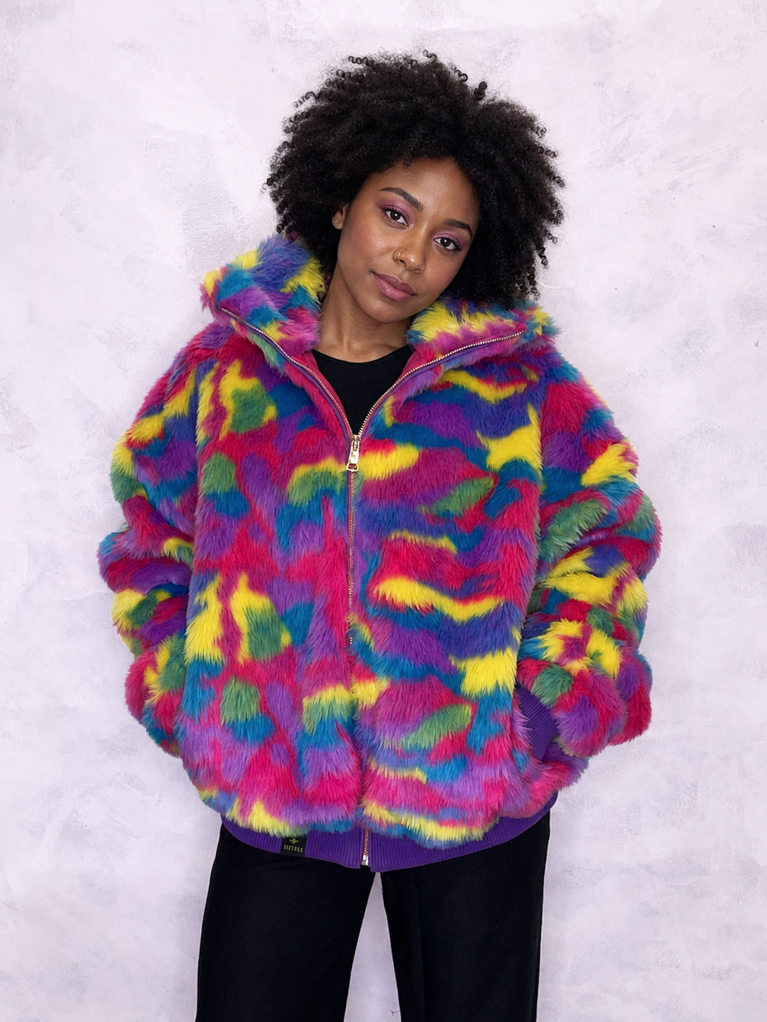 Vibrant multi-coloured faux fur bomber jacket made in the UK, featuring a mix of pink, blue, yellow, green and purple tones. The jacket is fully lined with side pockets, a high collar, and a front zip fastening. ribbed cuffs and waistband. Winter coat, party jacket, festival fur, bright bomber jacket