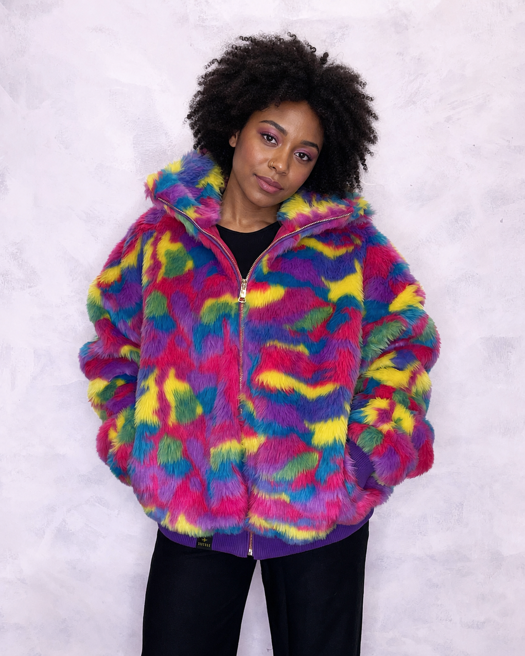 Vibrant multi-coloured faux fur bomber jacket made in the UK, featuring a mix of pink, blue, yellow, green and purple tones. The jacket is fully lined with side pockets, a high collar, and a front zip fastening. ribbed cuffs and waistband. Winter coat, party jacket, festival fur, bright bomber jacket