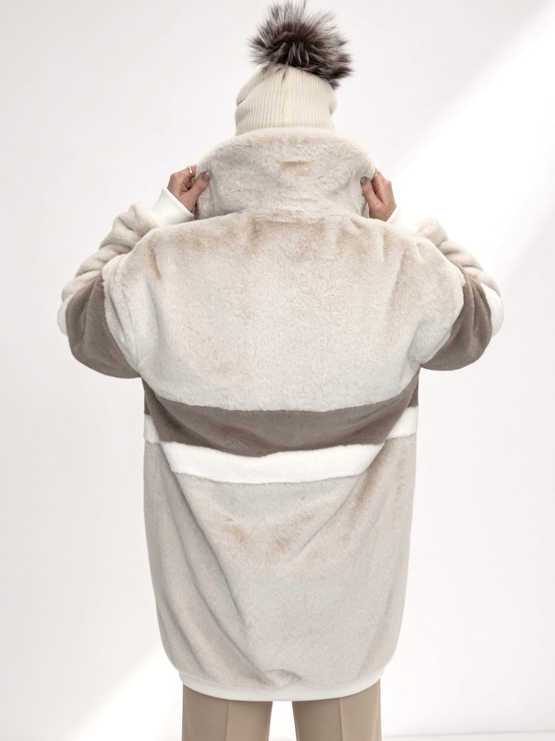 Handmade in the UK, this faux fur long bomber jacket features a soft plush texture with an oversized fit. Designed with deep side pockets, full duchess satin lining, and a durable YKK zip fastening. The jacket showcases a stylish colour block pattern in crisp cream with white and earthy taupe panels, combining warmth and statement style. Winter coat, collared jacket, long bomber jacket, cream coat, luxury jacket, high end fashion, ribbed cuff and waistband