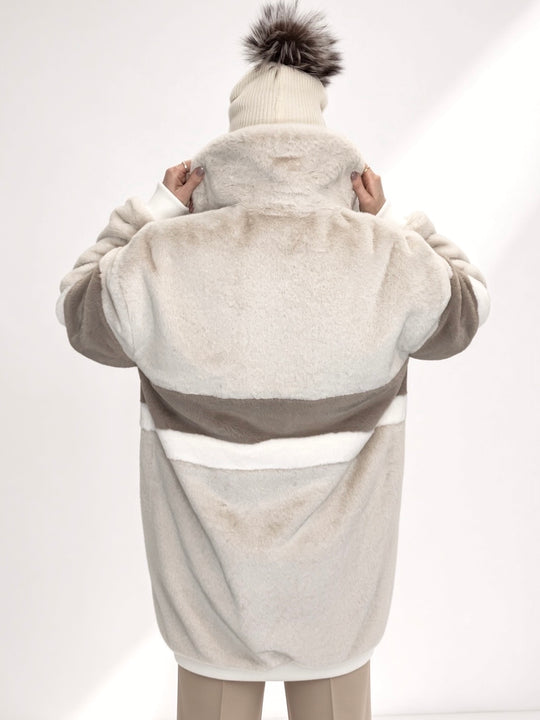 Handmade in the UK, this faux fur long bomber jacket features a soft plush texture with an oversized fit. Designed with deep side pockets, full duchess satin lining, and a durable YKK zip fastening. The jacket showcases a stylish colour block pattern in crisp cream with white and earthy taupe panels, combining warmth and statement style. Winter coat, collared jacket, long bomber jacket, cream coat, luxury jacket, high end fashion, ribbed cuff and waistband