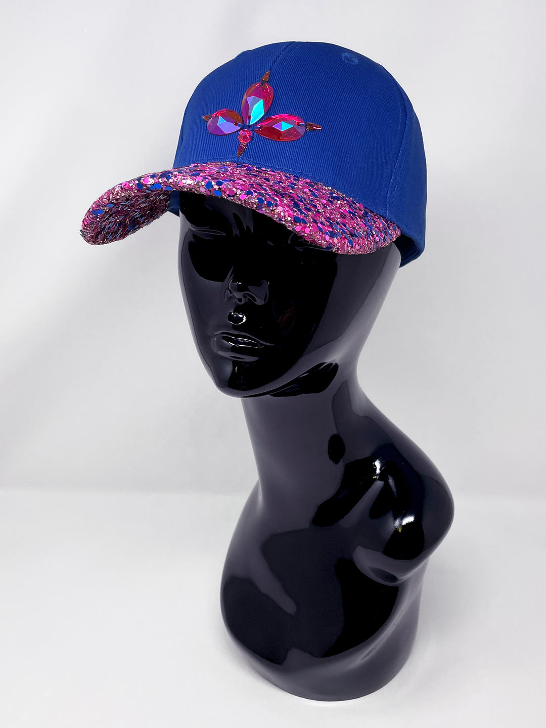 Blue curved peak cap with an embellished vibrant pink and blue glitter mix peak and 3D Jukebox logo emblem centre front, stylish streetwear, eye catching accessory, adjustable, velcro back, party hat, festival hat, urban, unique headwear, made in the UK