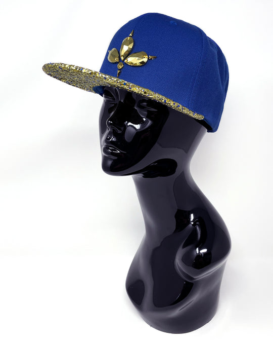 Blue flat peak cap with a gold and blue glitter mix peak. 3D Jukebox logo emblem centre front, stylish streetwear, eye catching accessory, adjustable, snapback, party hat, festival hat, rave, urban, crystals, festival fashion, rhinestones, unique headwear, made in the UK